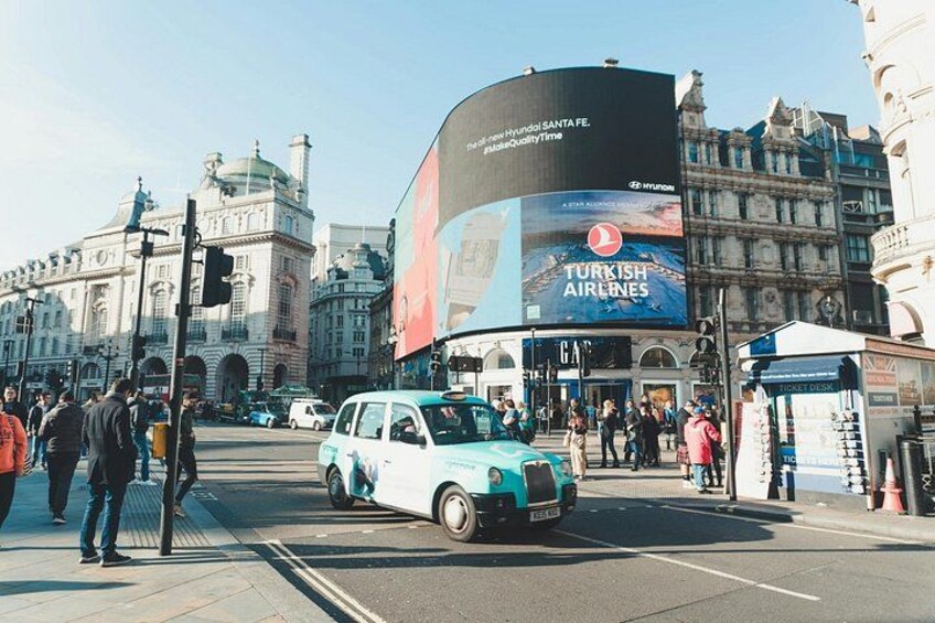 A busy urban street with a large billboard advertising Turkish Airlines, a historic building, and a blue taxi. 2
