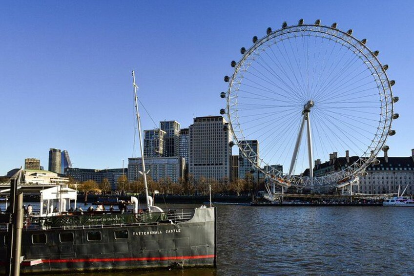 A Ferris wheel, a river, and a city skyline with buildings and a boat. 4