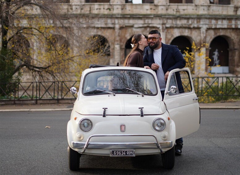 A white Fiat car parked in front of a historic building with arches. 5