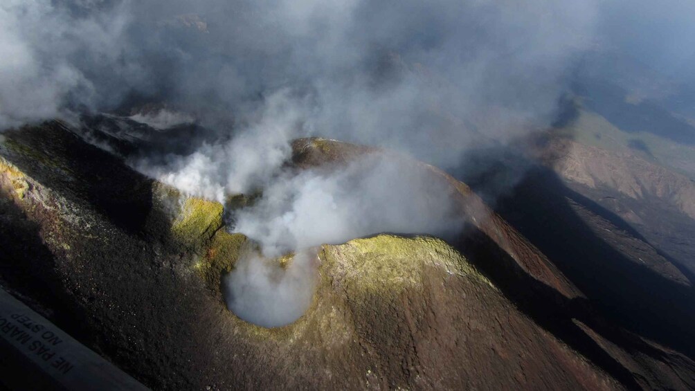 A volcanic crater with steam rising, surrounded by rugged terrain. 3