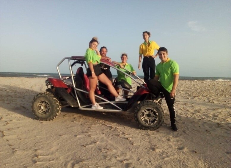 A group of people on a beach with a dune buggy. 5