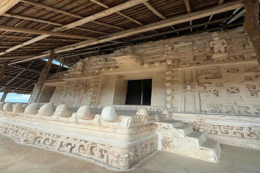 An ancient stone structure with intricate carvings and a thatched roof. 5