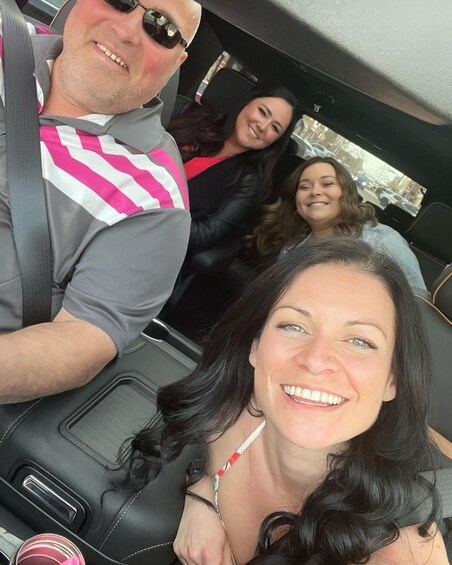 Three people in a car with a cityscape visible through the window. 4