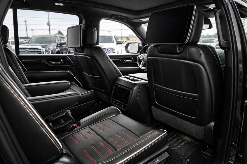 A car's interior with black leather seats, a central console, and a rearview mirror. 5
