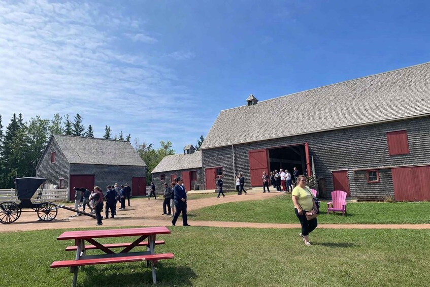 A historical site with wooden buildings, a picnic table, and a covered wagon. 2