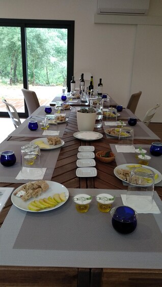 A long wooden table set for a meal with plates of food, glasses, and bottles. 3