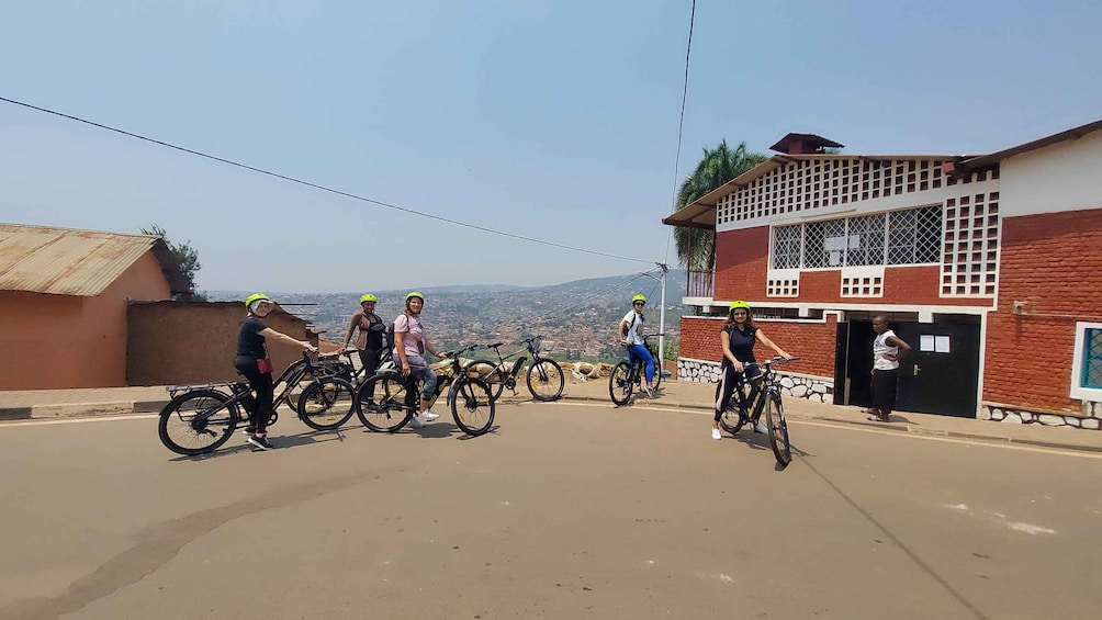 A group of cyclists on a road with a view of a cityscape and a building with a red and white facade. 4