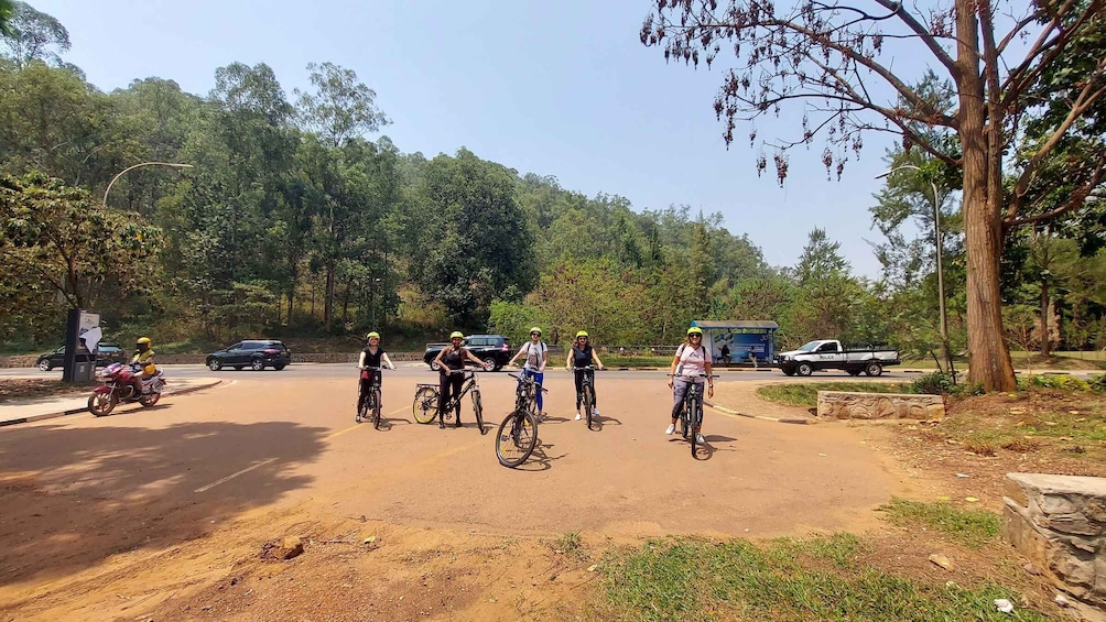 A group of cyclists on a dirt path with cars and a police vehicle in the background. 3