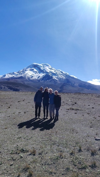 A group of people standing on a barren landscape with a snow-capped mountain in the background. 4