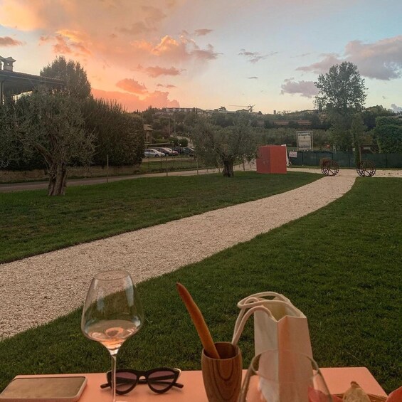 A sunset view over a gravel path with a table set for a meal, surrounded by greenery and trees. 4