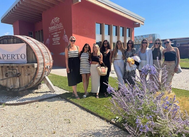A group of people in front of a red building with a sign that reads 'PODERE & FOLLI WINERY.' 5
