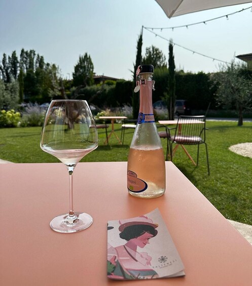 A bottle of Bésoin wine and a wine glass on a table outdoors. 3
