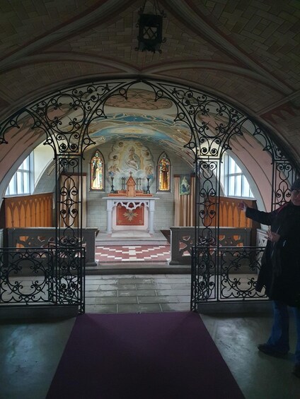 An interior of a church with arched ceilings, stained glass windows, and a central altar. 3