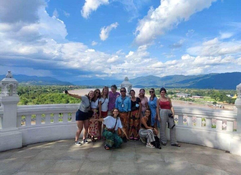 A group of people on a balcony overlooking a scenic landscape with mountains and a river. 5