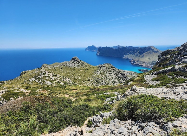 A mountainous landscape with rocky terrain and sparse vegetation, overlooking a deep blue sea with a clear sky. 2