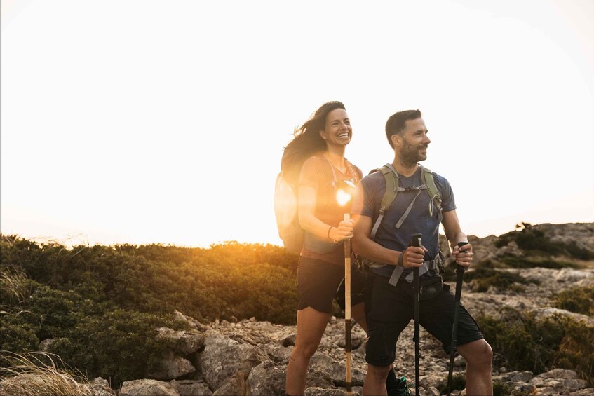 Two hikers with backpacks on a rocky terrain during sunset. 3