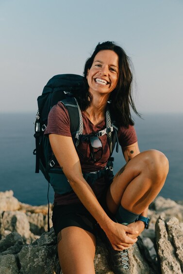 A person sitting on a rocky outcrop with a backpack, overlooking a vast landscape. 5