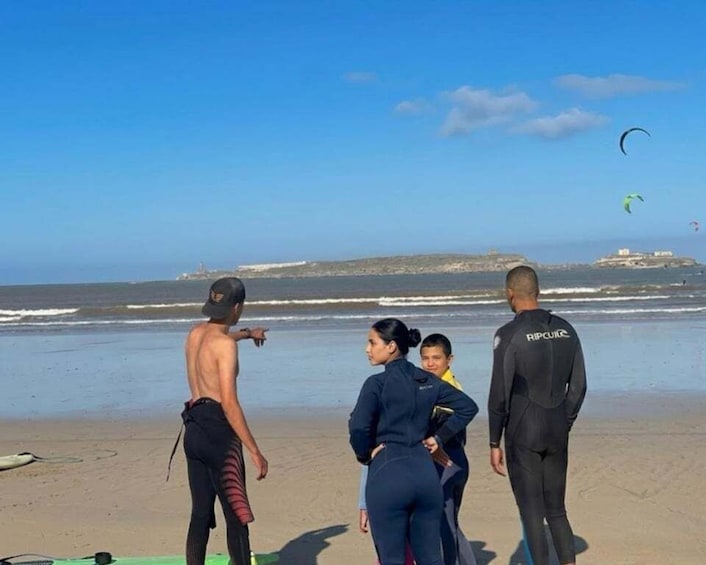 A group of people on a beach with a clear sky, ocean, and distant land. 5