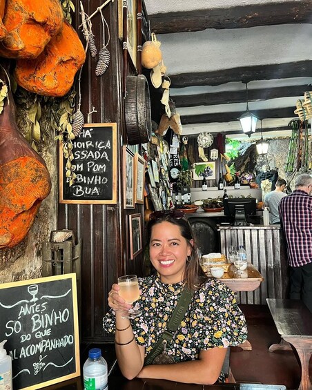 A person holding a drink in a rustic restaurant with wooden walls and various decorations. 2