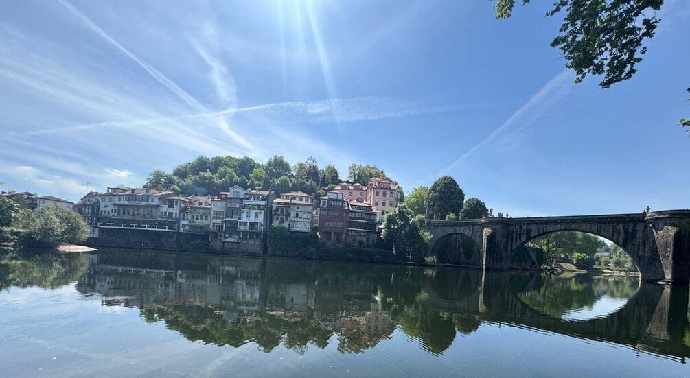 A calm river reflecting buildings and a stone bridge. 3