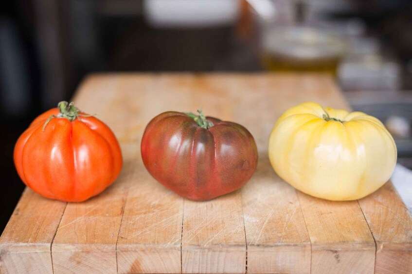 Three tomatoes on a wooden cutting board. 4