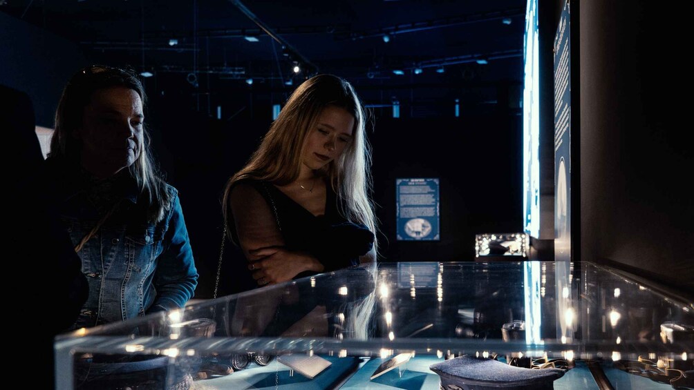 Two people examining a display case with various items inside. 5