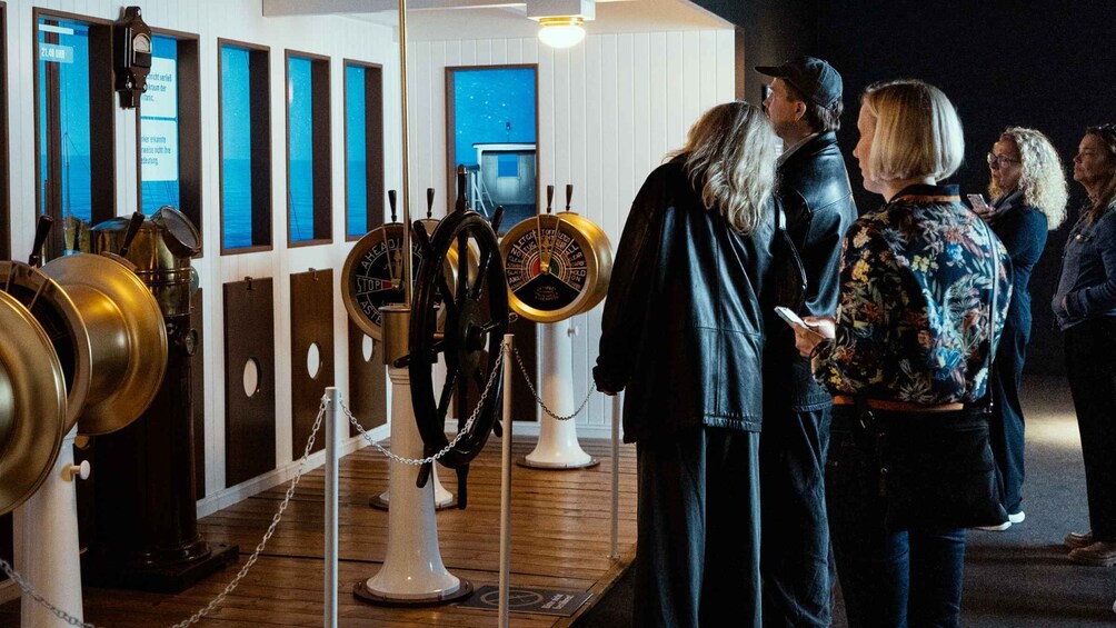 A group of people observing maritime navigation instruments in a museum. 4