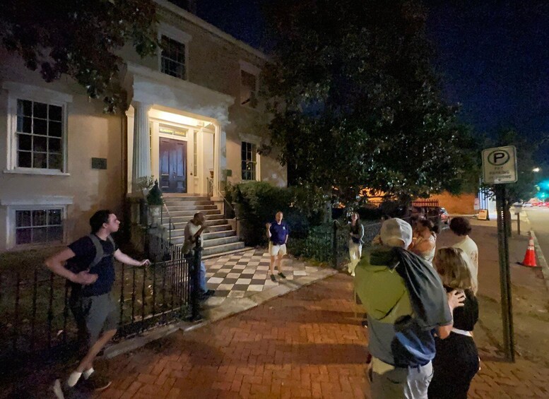 A group of people gathered outside a building with a checkered pavement and a 'P' parking sign. 5