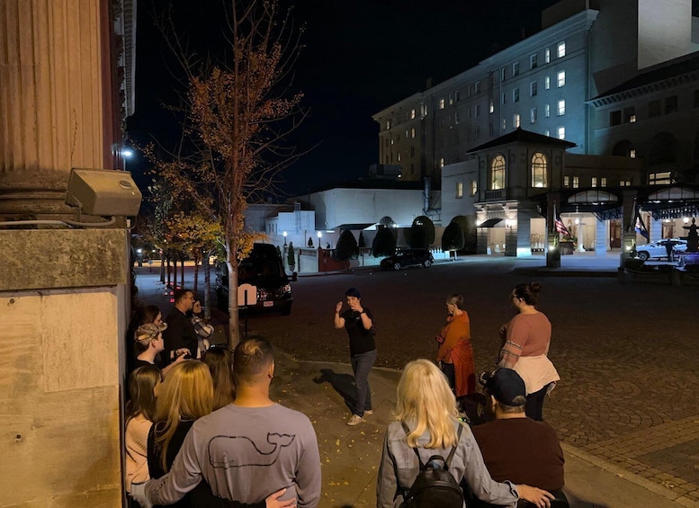 A nighttime urban scene with people gathered on a street, a building with illuminated windows, and a tree in the foreground. 1
