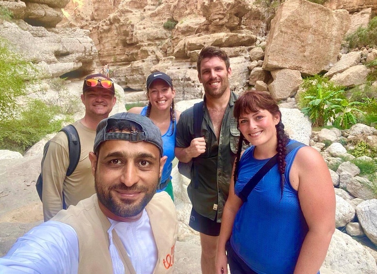 A group of people standing in a rocky outdoor area with greenery. 1