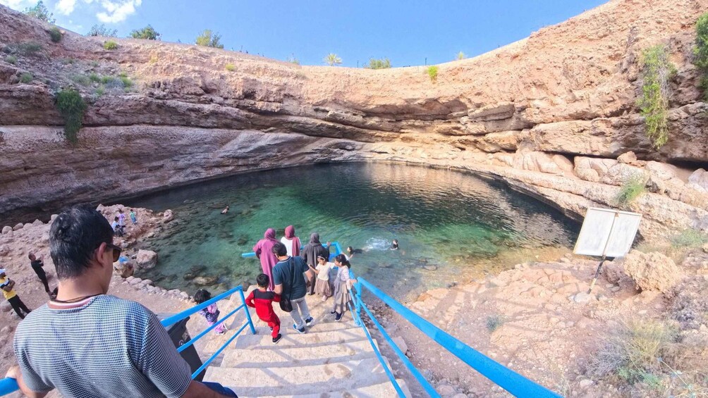 A group of people at a natural pool surrounded by rocky cliffs. 4