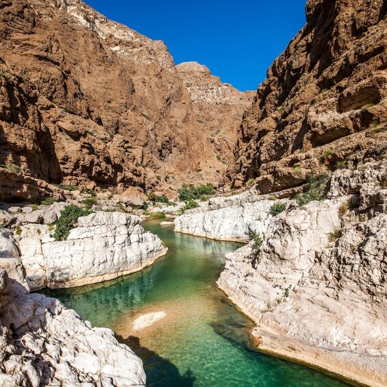 A clear river winding through rocky terrain with white cliffs. 2