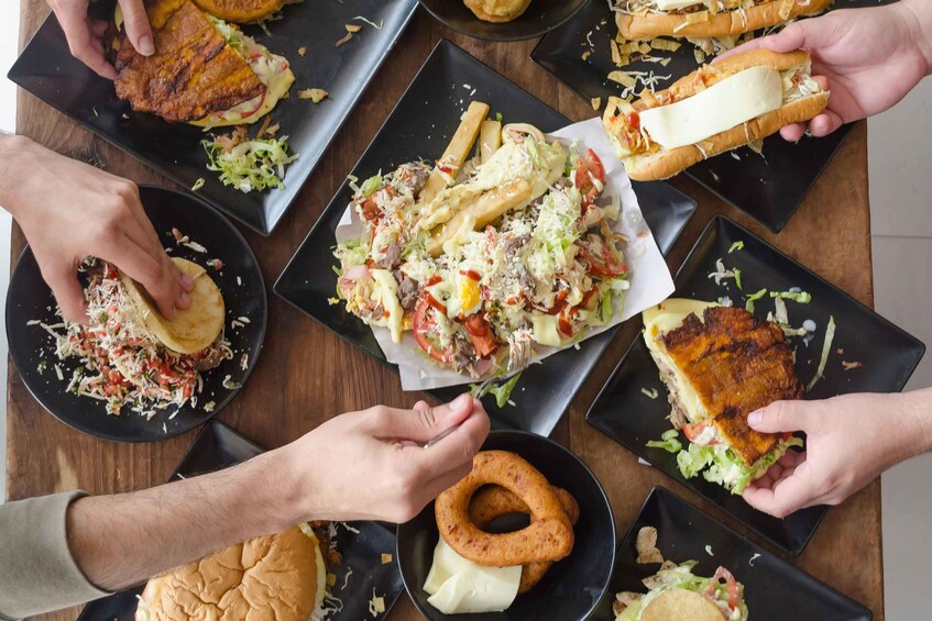 A group of people sharing a meal with various dishes including burgers, fries, and sandwiches. 3