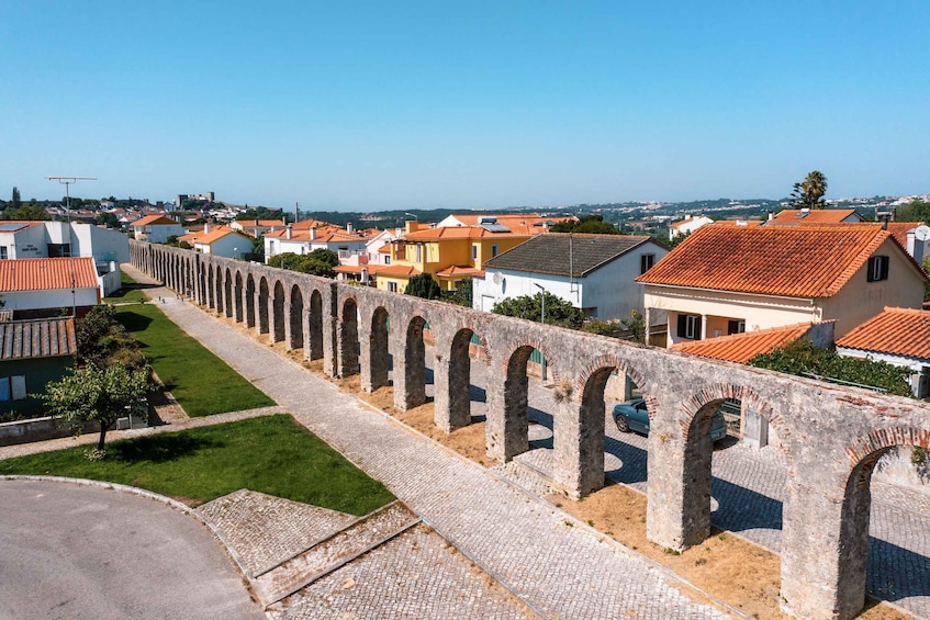 A stone bridge with arches, a paved path, and residential buildings with red-tiled roofs. 5