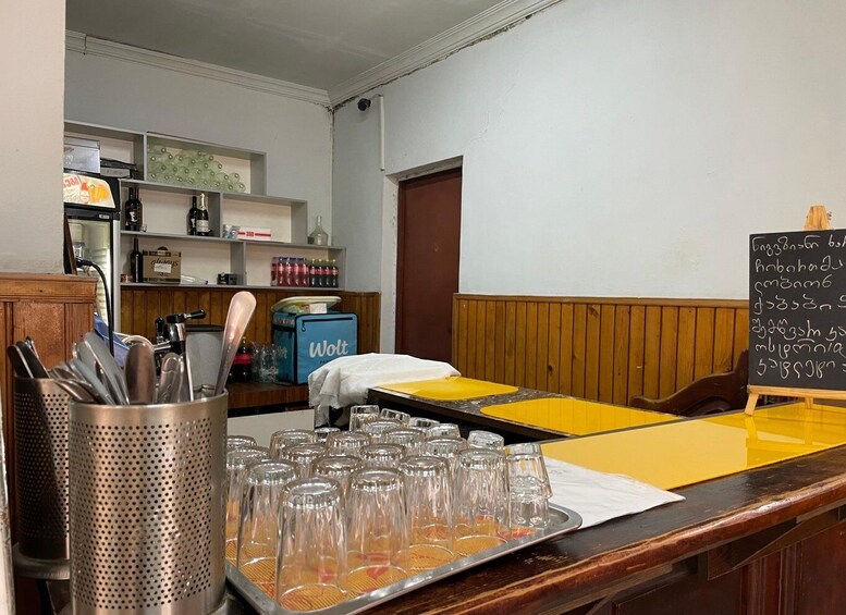 A bar area with a chalkboard menu, glasses on a tray, and a blue cooler. 3