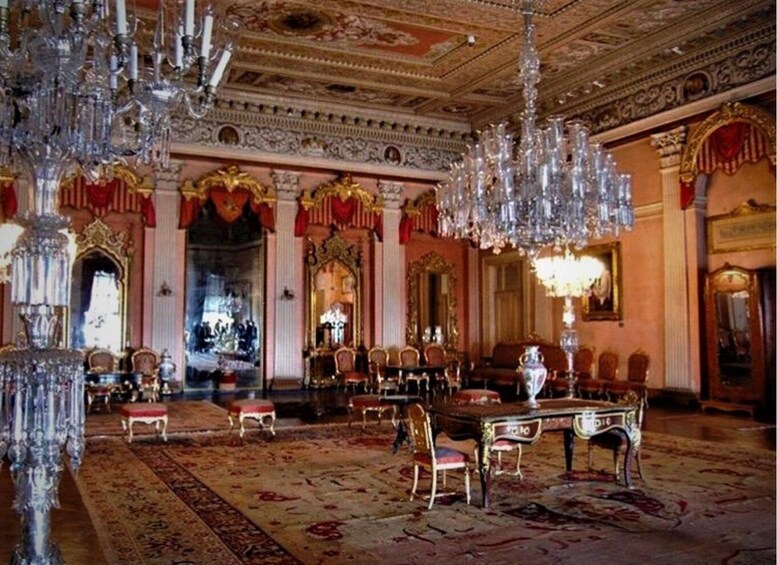 An opulent room with ornate chandeliers, red and gold decor, and a large mirror. 2
