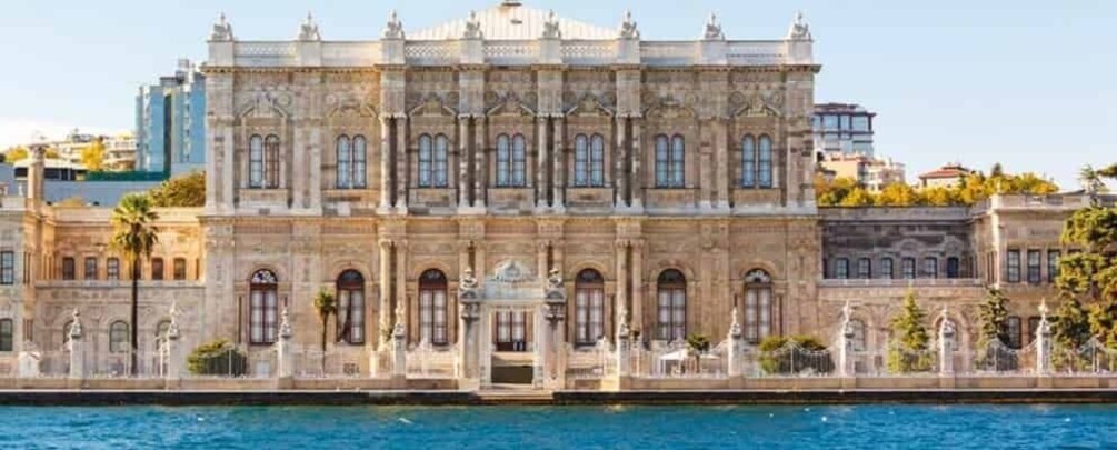 A historic building with ornate architecture, a waterfront, and a clear sky. 5