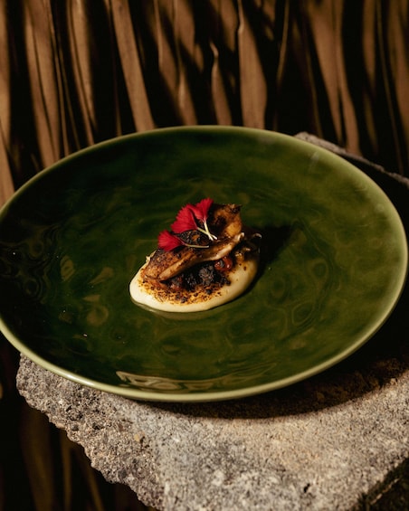 A green plate with a food item, possibly a fish or meat, on a textured surface. 1