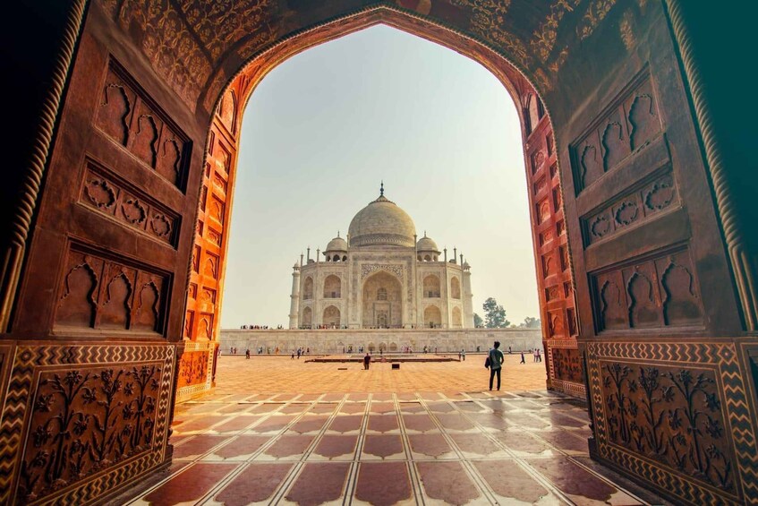 The Taj Mahal through an ornate archway, with a tiled courtyard in the foreground. 4
