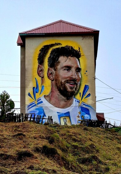 A mural of a football player on a building with a red roof. 1