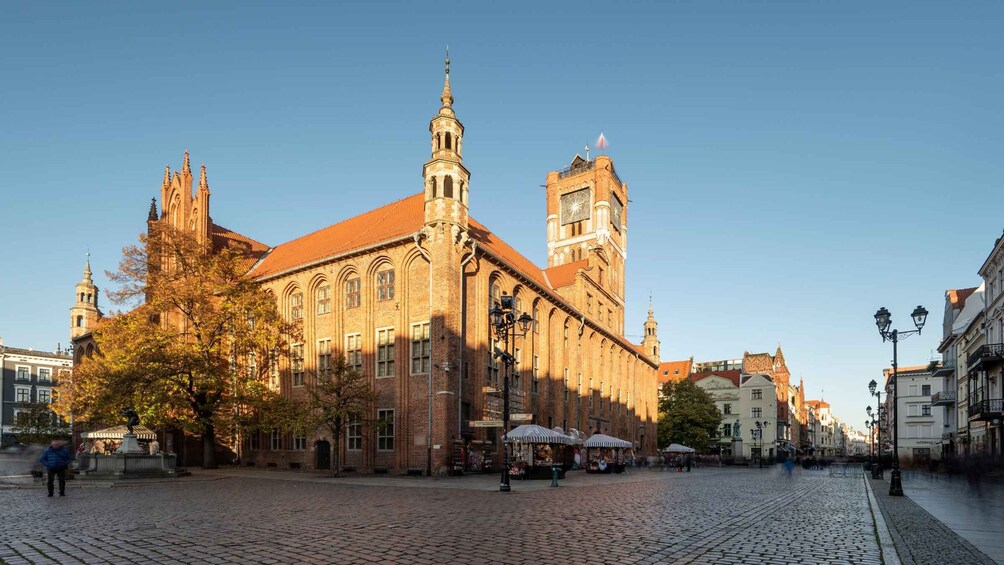 A historic building with a clock tower, cobblestone streets, and autumn foliage. 2