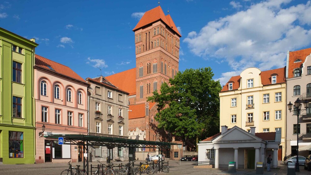 A historic building with a tower, colorful facades, and a covered bike parking area. 5
