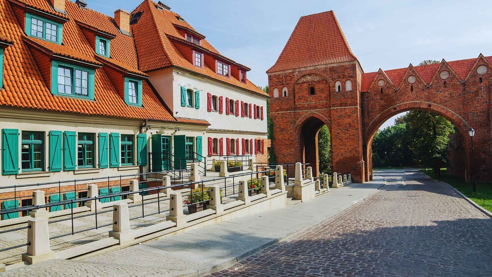 A cobblestone street lined with traditional buildings, a brick archway, and a red-tiled roof. 3