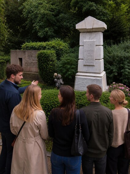 A group of people visiting a memorial with inscriptions and a statue. 1