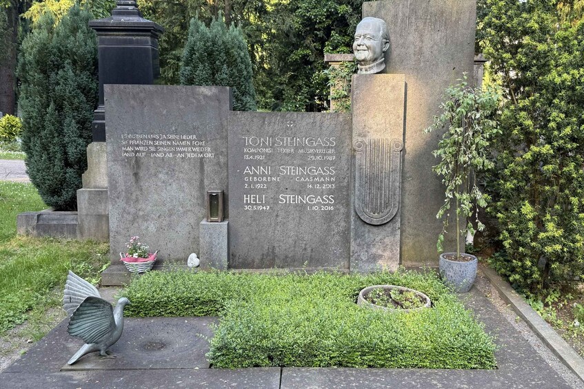 A memorial with inscriptions, a bust, and a bird sculpture. 2