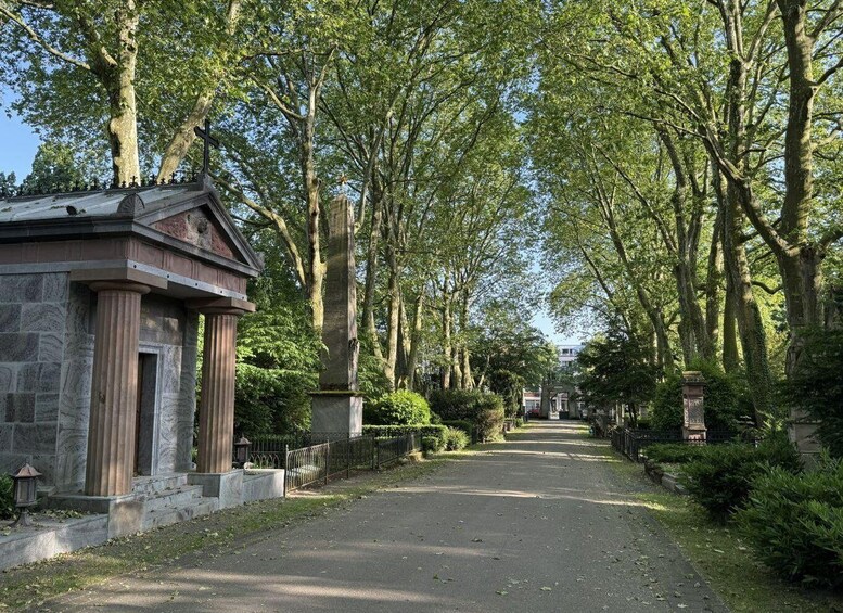 A tree-lined pathway leading to a stone structure with columns. 3