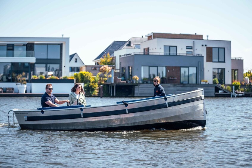 A narrow boat with three people on a calm water body, surrounded by modern houses. 4