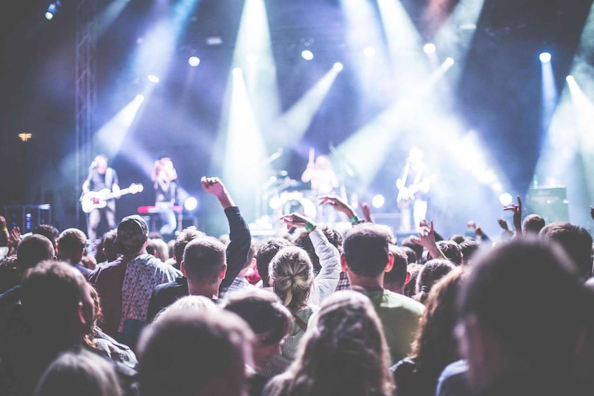 A concert with a crowd facing a band performing on stage. 1