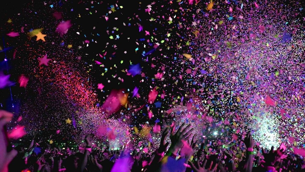 A crowd at a concert with colorful lights and confetti. 3