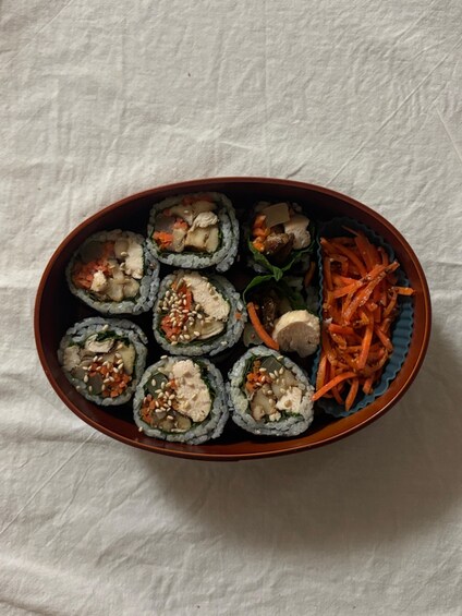 A bento box with sushi rolls and shredded carrots. 2